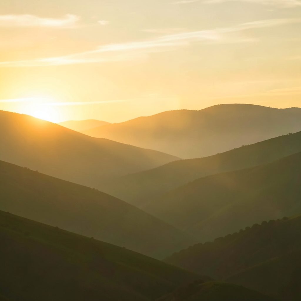 A warm-toned abstract image with soft golden and olive hues suggesting a sunrise over rolling hills, evoking hope and a new day.